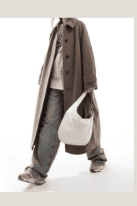 Fall streetwear look featuring oversized brown trench coat, wide-leg denim, beige hoodie, and chunky sneakers. Casual modest layering outfit for hijabis in neutral tones.

